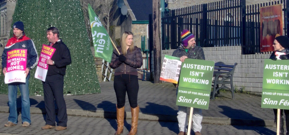 people are holding green signs near a fence