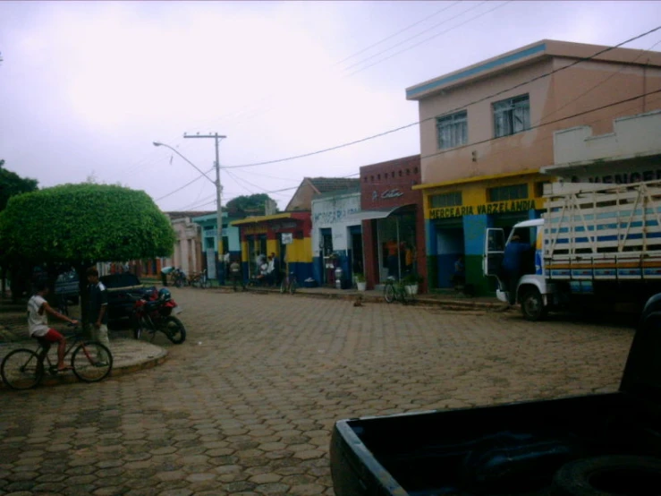 a dirt road with several parked cars and several people riding bikes