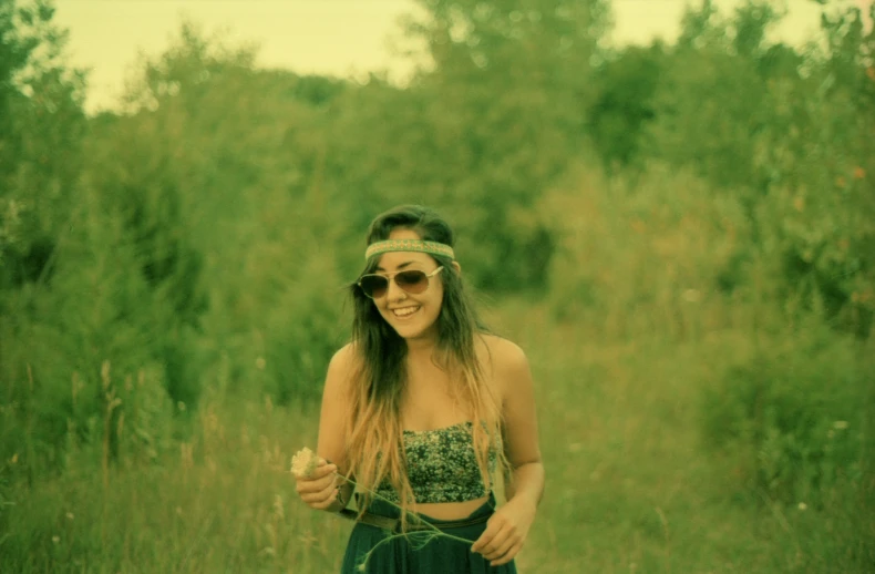 a woman in sunglasses standing in the grass