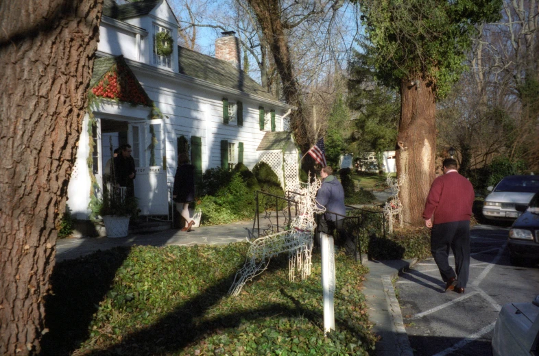 a man and woman walking on a sidewalk past a house