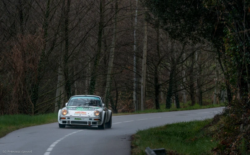 a car drives down the road beside some trees