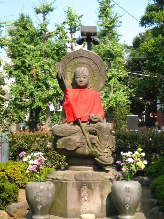 a statue in a garden with flowers surrounding it