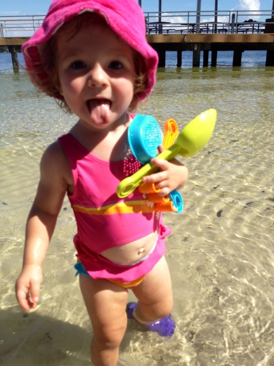 a little girl in pink bathing suit on beach