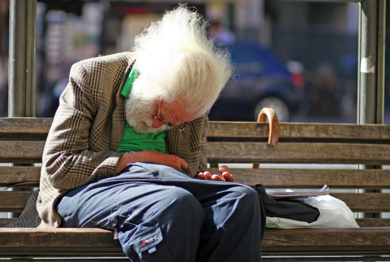 an old white haired man sitting on top of a bench