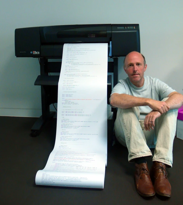 a man sits in front of a large sheet of paper