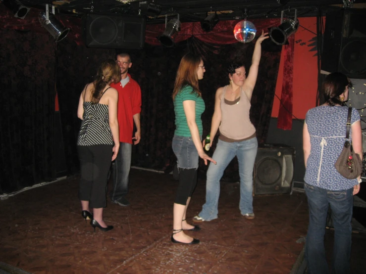 women standing on a stage, one of the woman is spinning a ball in front of her