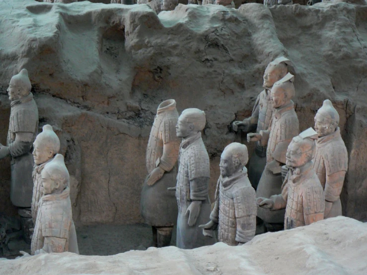 the statues of people are lined up in front of a mountain