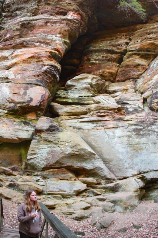 a lady is standing on a walkway leading to some rocks