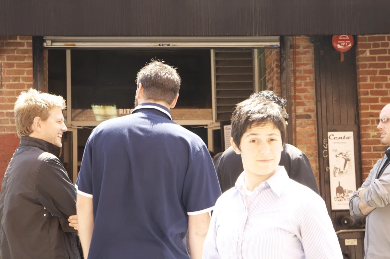 three men and one woman are in front of a building