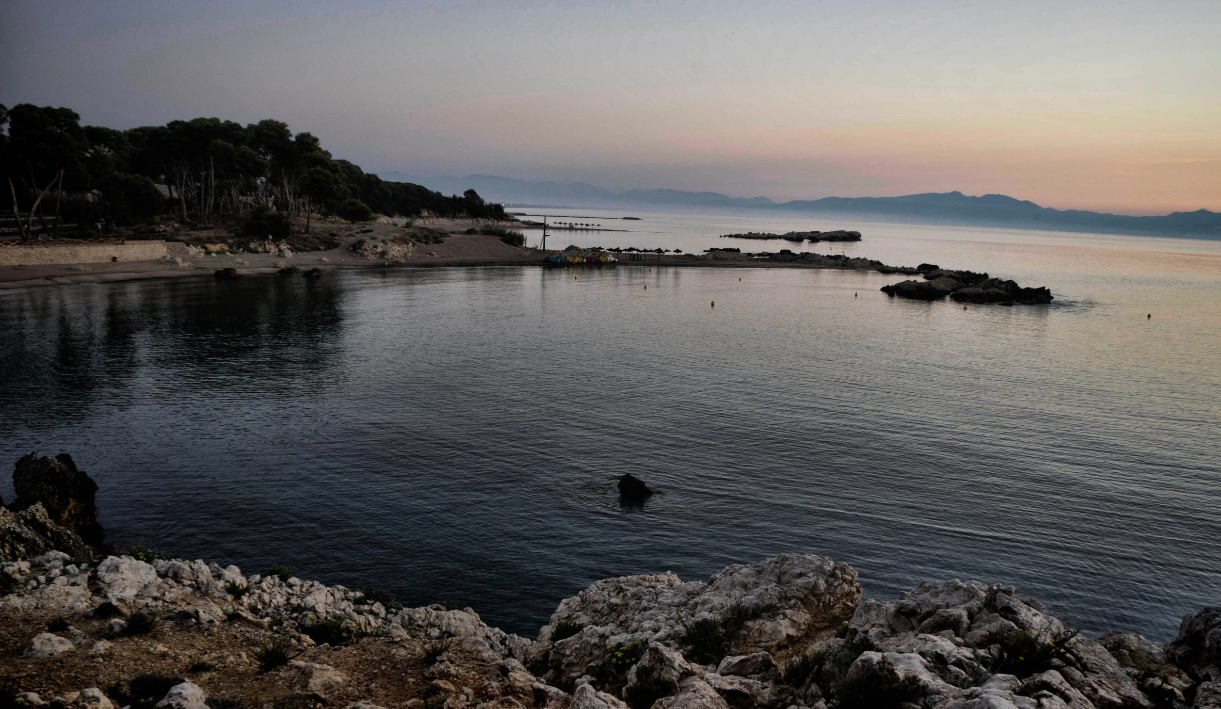 an island with small boats at dusk on water