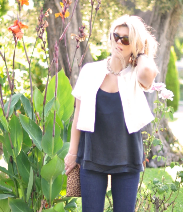 a woman is standing next to some flowers holding a brown purse