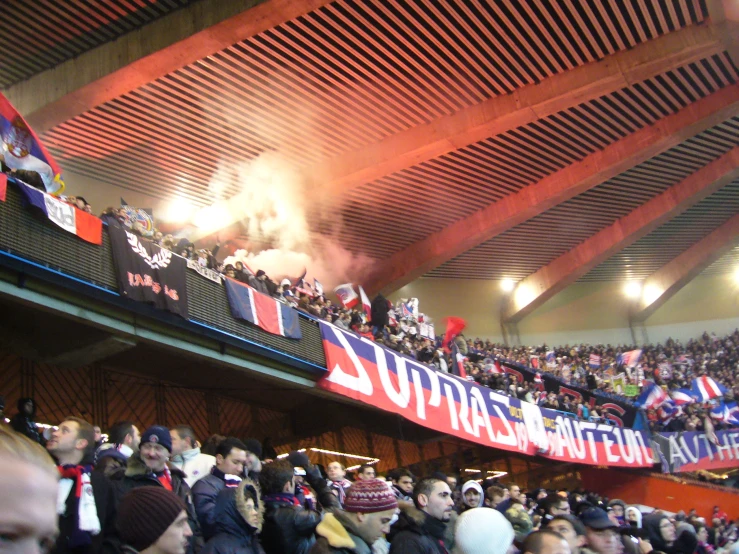 an indoor stadium full of people, one has an banner that reads