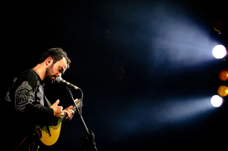 a man standing in front of a microphone playing a guitar