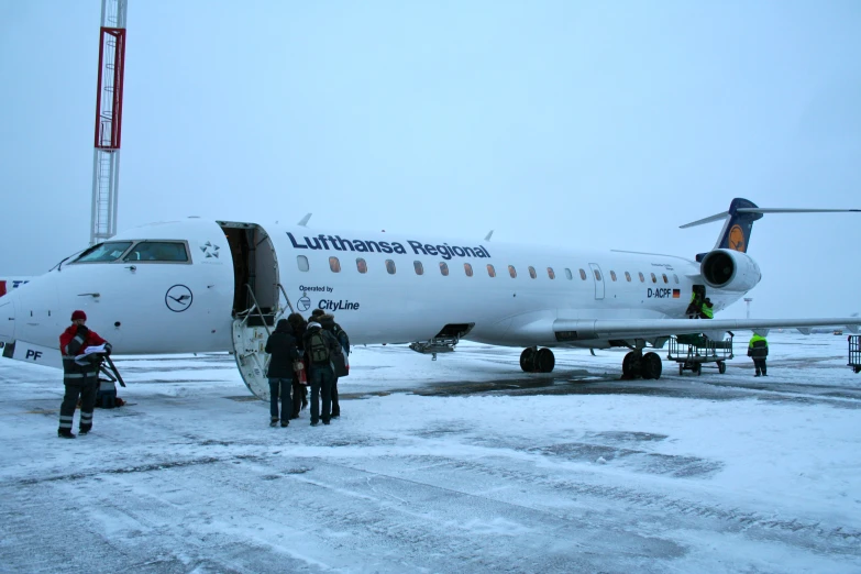 people loading and unloading an airplane with it's doors open