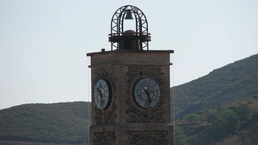 a clock tower sitting in front of a green mountain