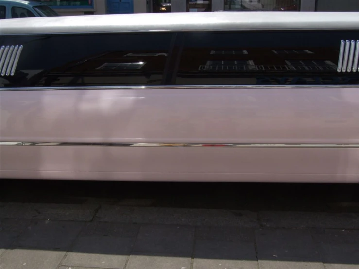 a very thin pink car parked in the parking lot