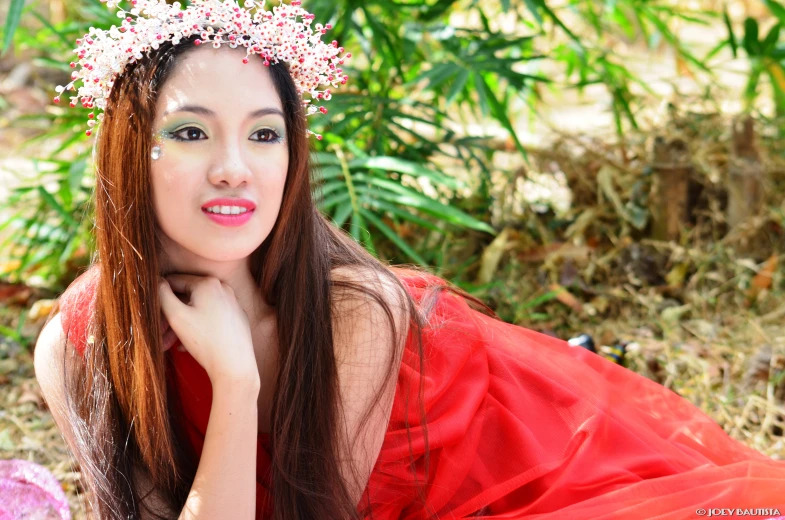 a woman sitting on the ground wearing a red dress