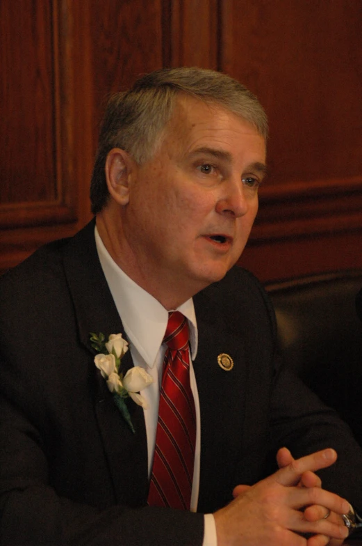 a man in a suit is talking in a wooden room