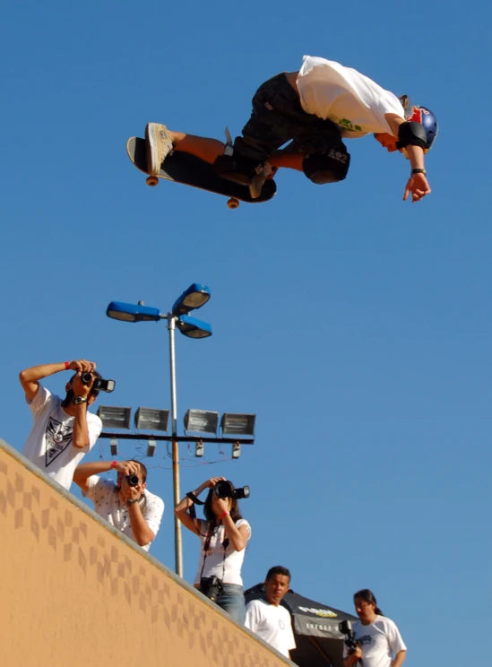 a skateboarder performs a trick above the crowd at a competition