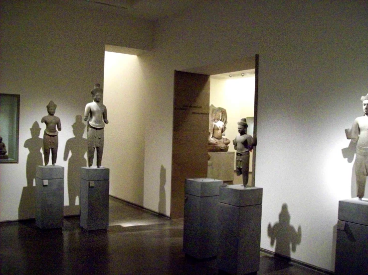 two sculptures of people on display with another figure