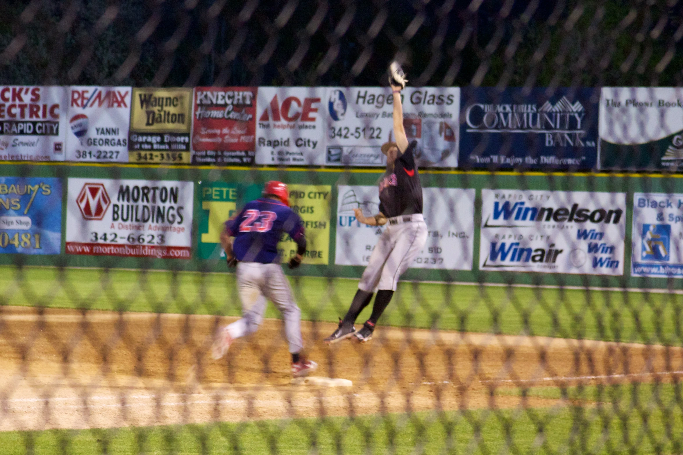 a man in black and white baseball uniform jumping up with bat in air