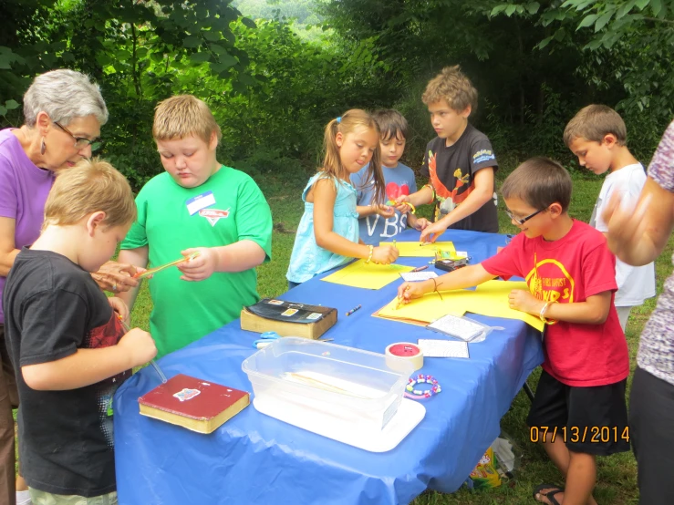 several children are standing around a cake in front of a woman