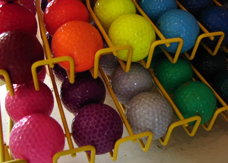 several colorful golf balls are hanging in the rack