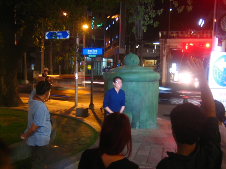 two people standing on the sidewalk near a trash can