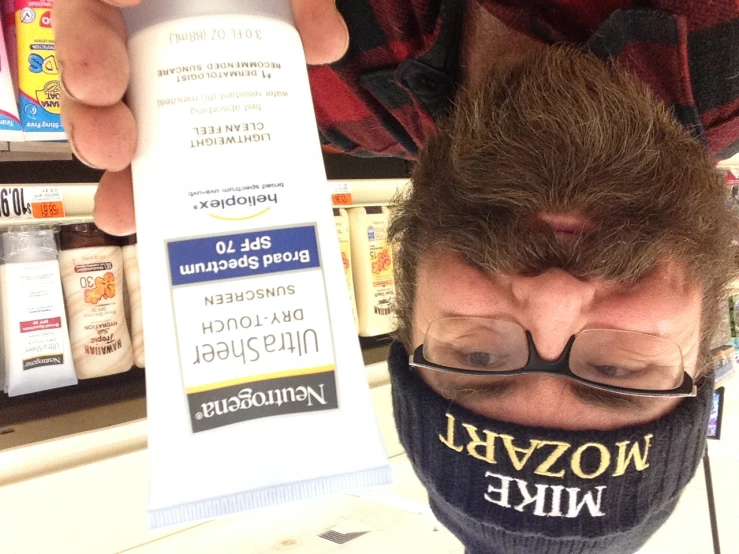 man in a bookstore holding up a tube of sunscreen