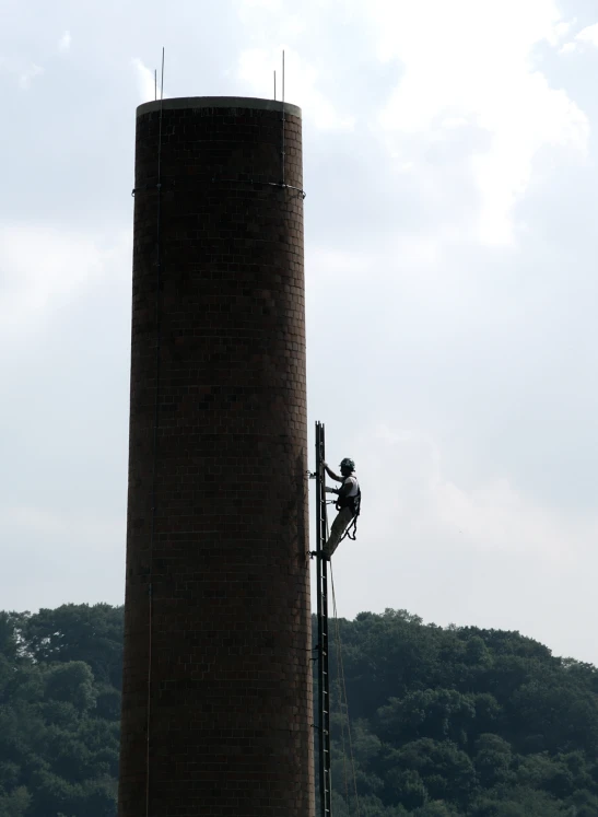 man using scaffolding to repair a brick water tower