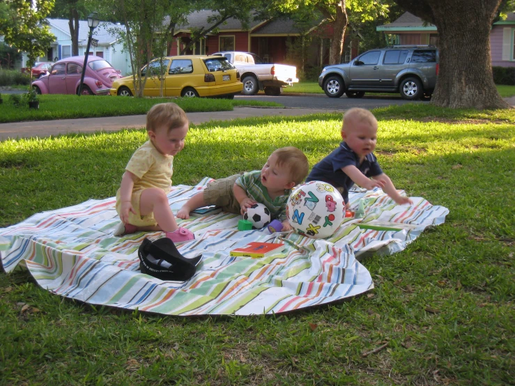 three small children laying on the ground on a blanket