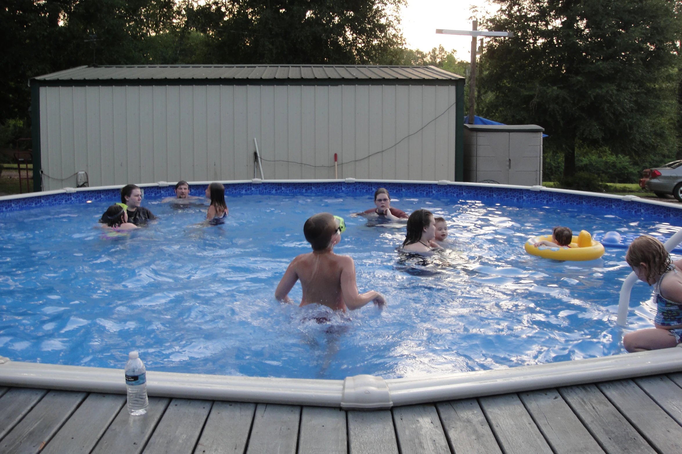 a group of people in an above ground pool with boogie board