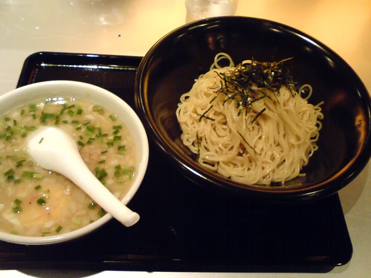 a black tray topped with two bowls filled with soup