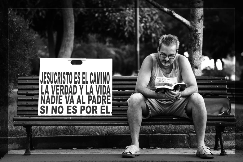 a man reads a book while sitting on a park bench