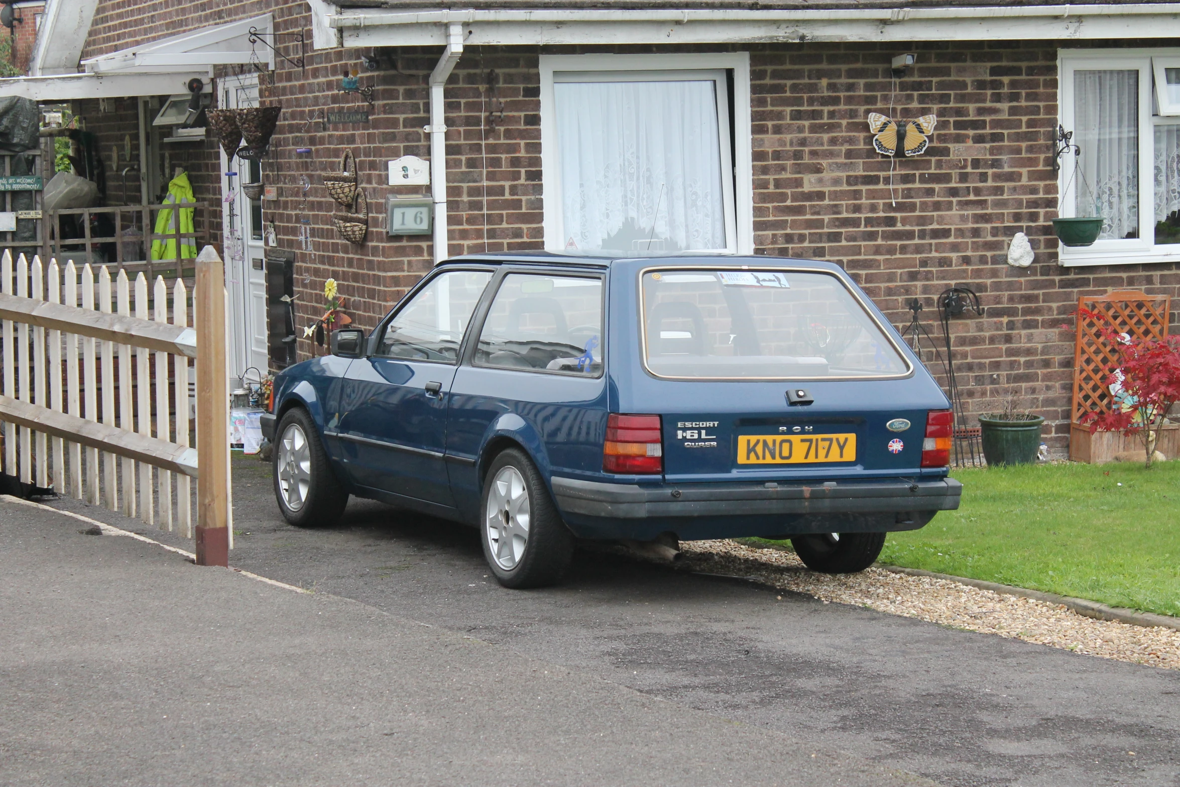 the blue car is parked in front of the brick house