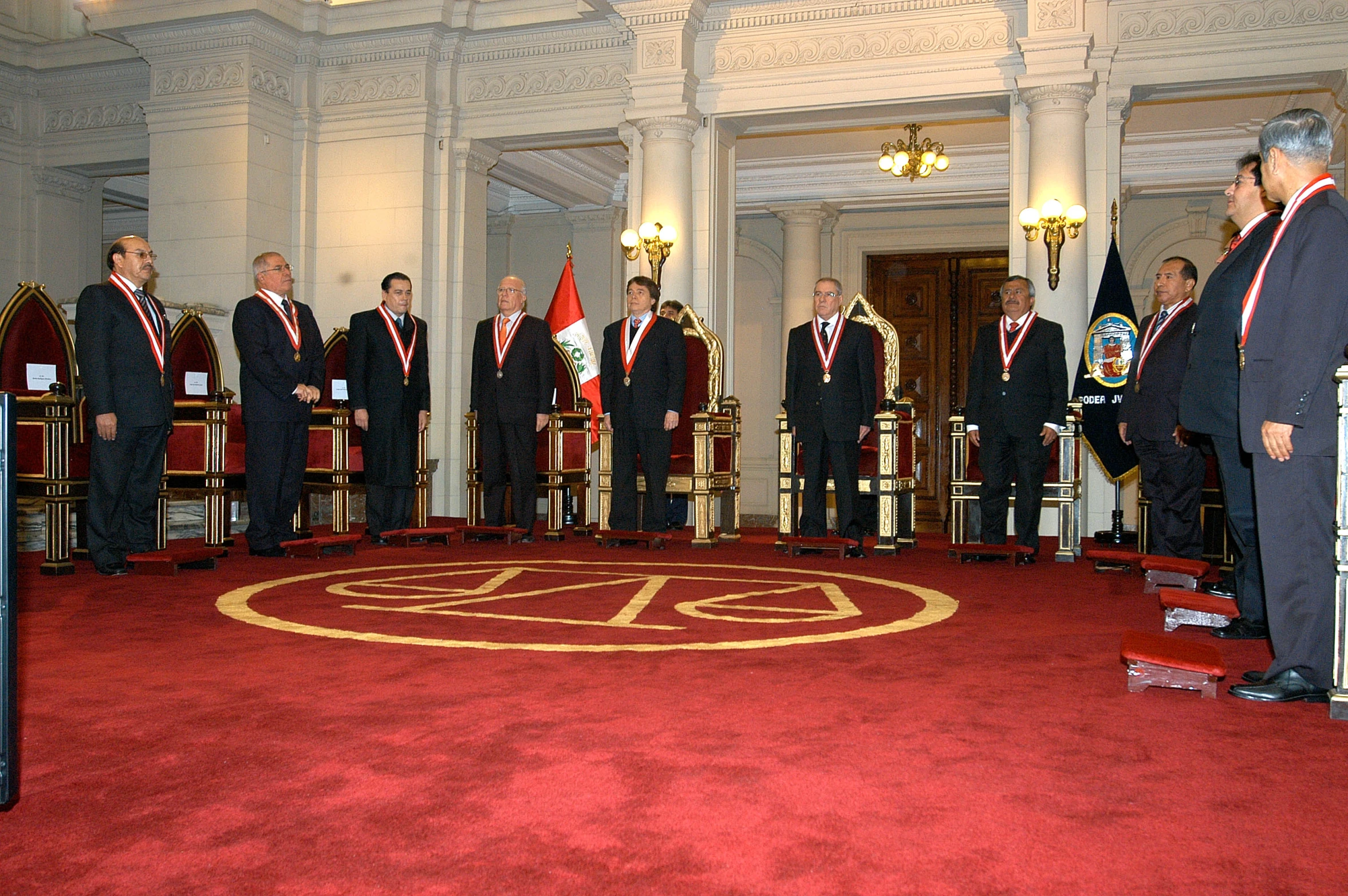 several people in suits standing around chairs at a podium