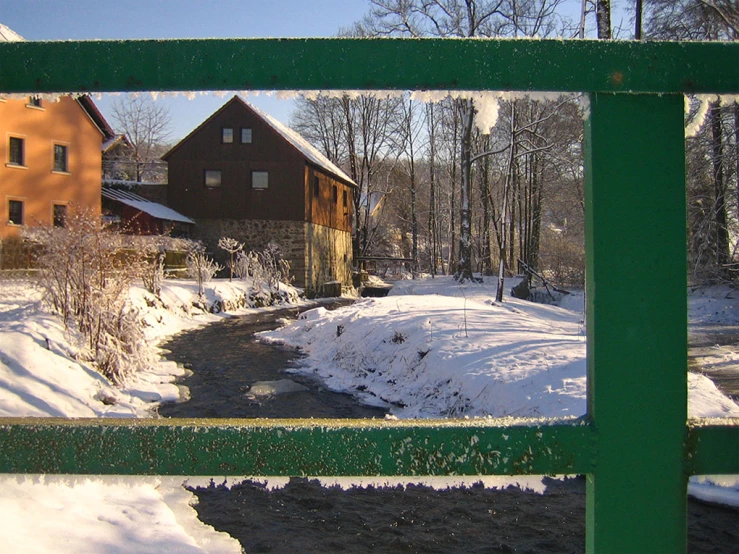 a stream near a barn in the snow