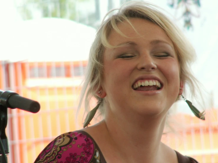 a woman smiling at soing while singing into a microphone