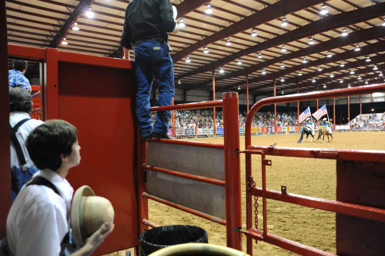 a man on top of a fence at a rodeo