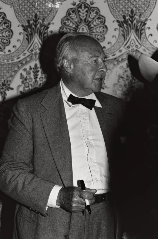 an old man in a suit and bow tie looking off to his right