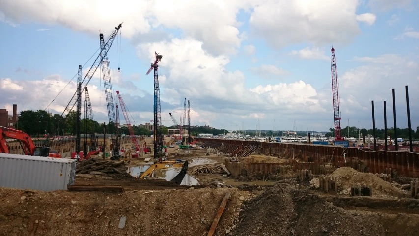 several construction cranes and buildings in a city under cloudy skies