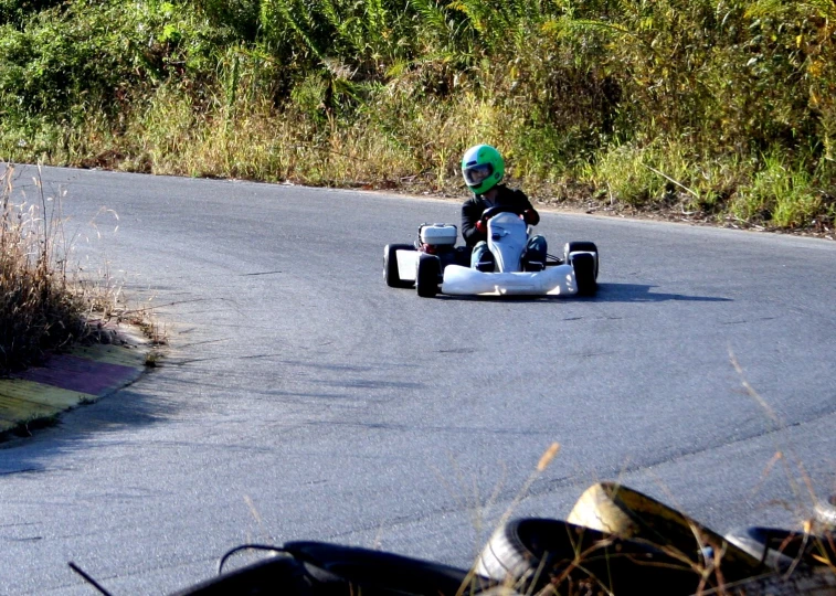 a small boy driving a go kart down a country road