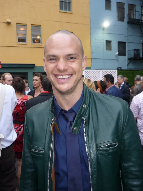 a man with a bald head wearing a green leather jacket