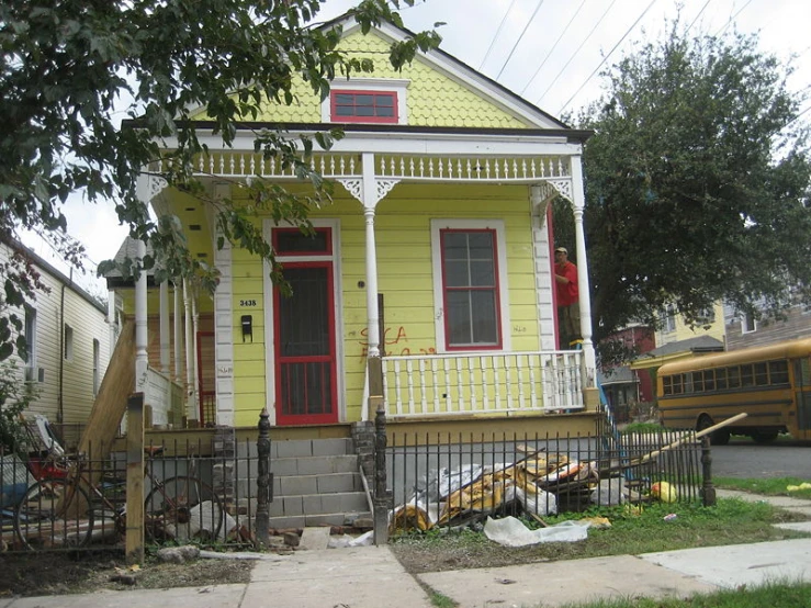 an old house is painted bright yellow with red trim