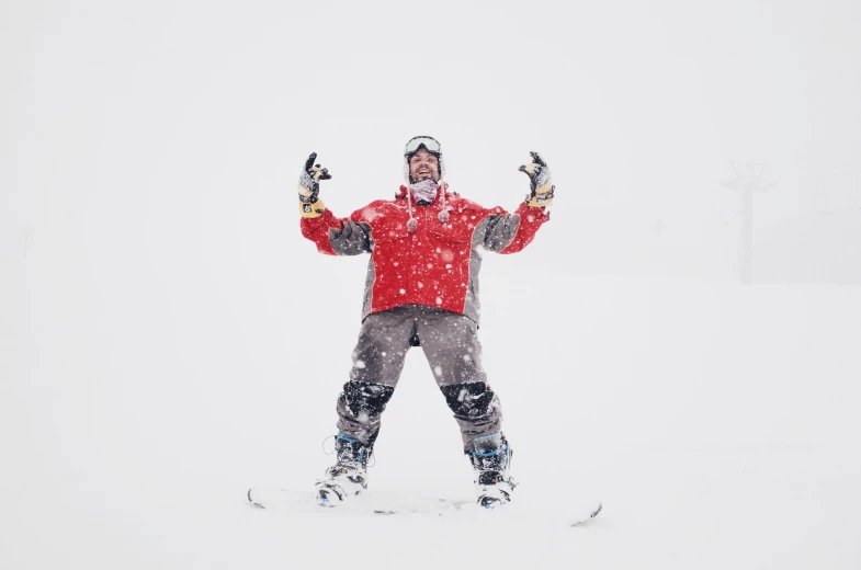 a snowboarder is standing on the snow with his arms out