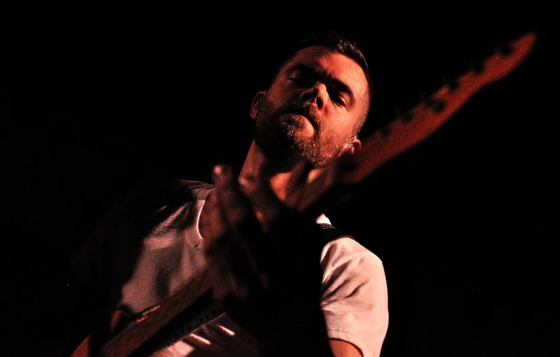 a man playing an electric guitar and singing in a dark background