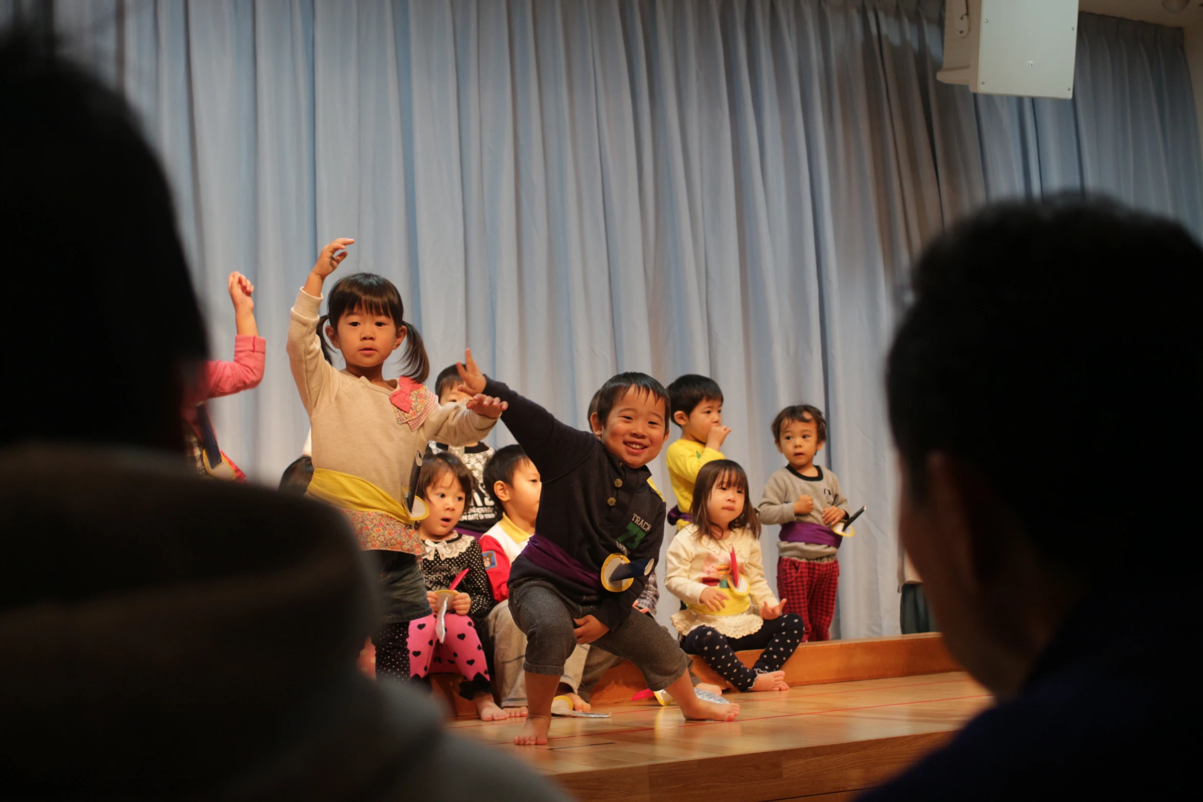 a group of children on a stage with one of them raising their arms