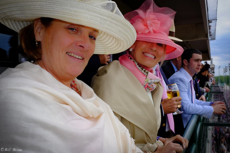 three ladies in hats are sitting on a balcony