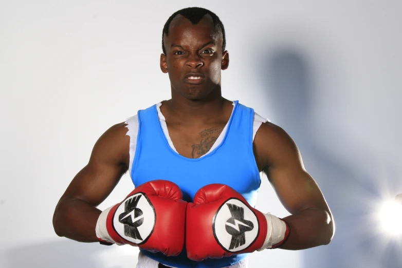 a man posing for a po in a tank top and boxing gloves