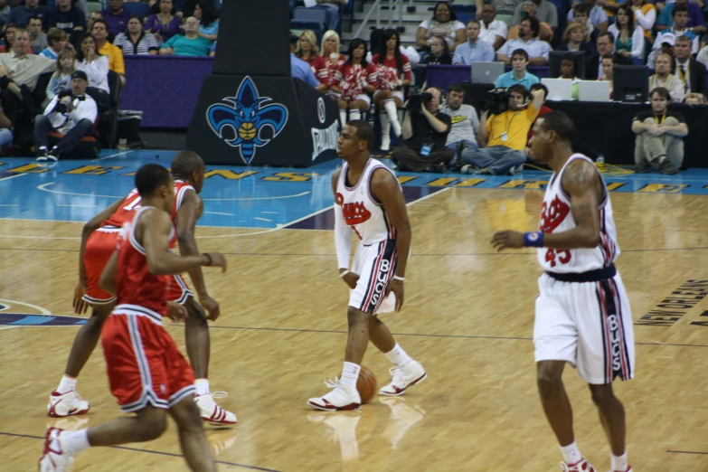 several men walking on a basketball court holding basketballs